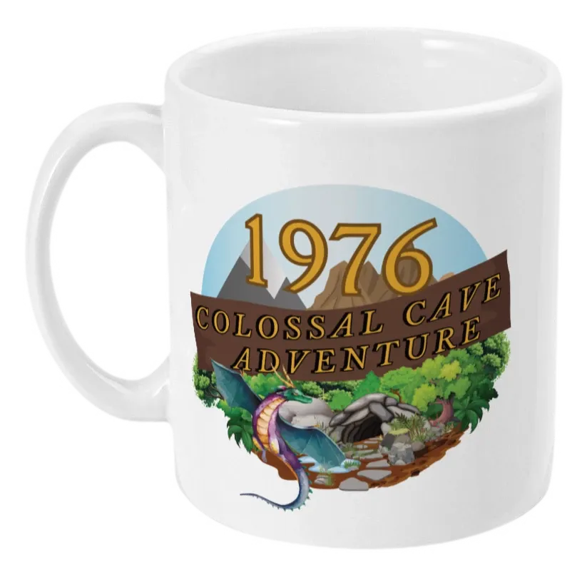 White mug with words,1976,colossal cave adventure,circular picture of a dragon,cave and woodland,blue sky,daytime