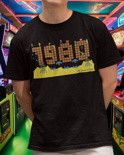 Black t shirt with a large 1980 in pixels in orange brown with some notable arcade video gaming sprites from 1980 around it