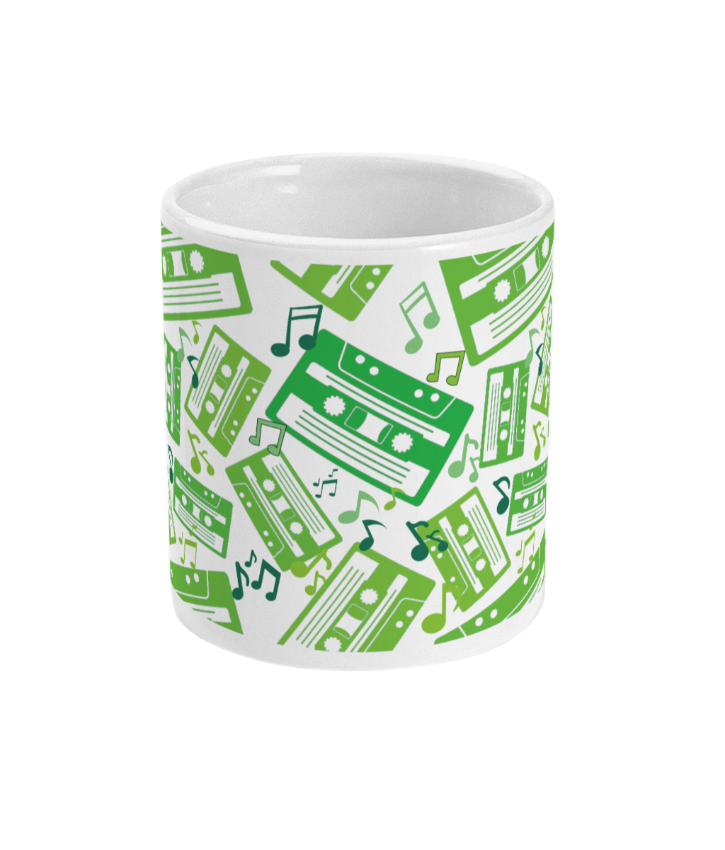 White mug with green toned music notes and cassette tapes spread out at different angles in different shades of green around the sides and front.