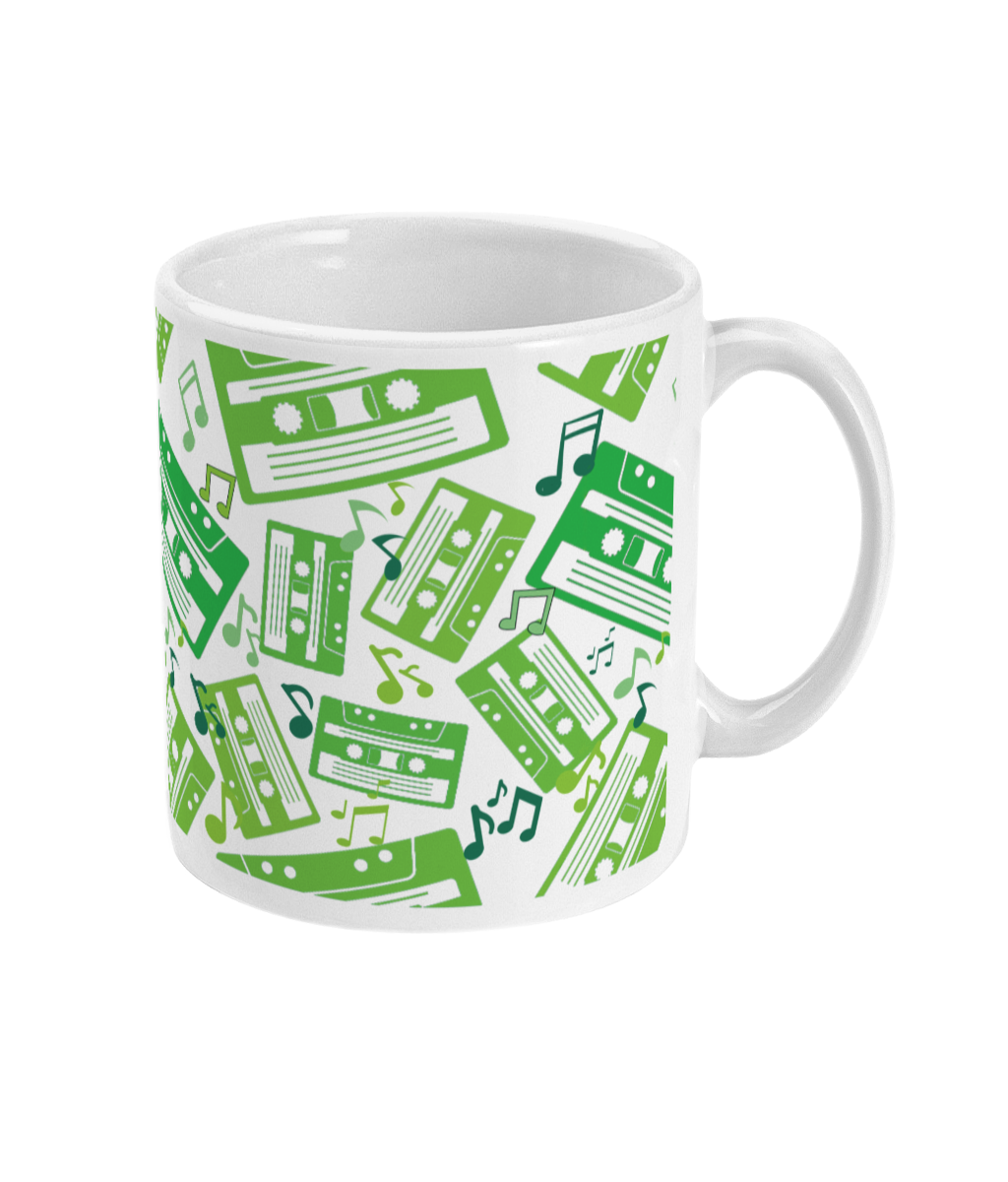 White mug with green toned music notes and cassette tapes spread out at different angles in different shades of green around the sides and front.