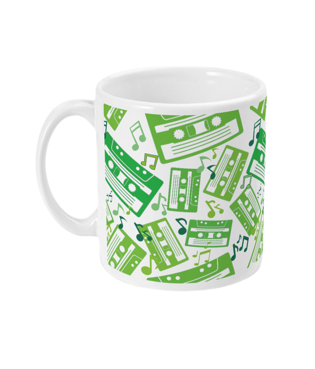White mug with green toned music notes and cassette tapes spread out at different angles in different shades of green around the sides and front.