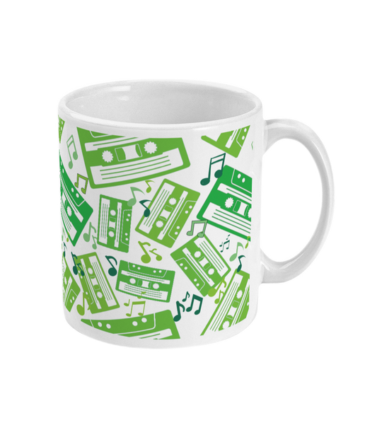 White mug with green toned music notes and cassette tapes spread out at different angles in different shades of green around the sides and front.