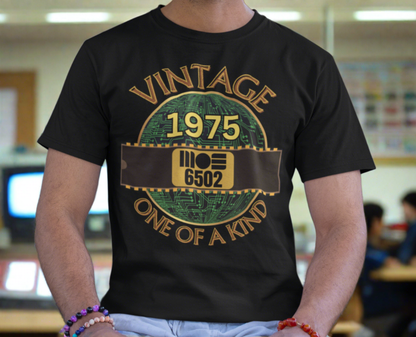 Black T-shirt with a gold circle with a basic representation of a circuit board in green and a 40 pin chip across the front with MOS 6502 and 1975 written on it. Vintage one of a kind around the circle