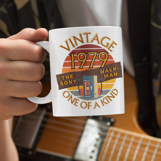 White mug  with words vintage,1979,the sony walkman,one of a kind, image of the original TPS-L2 model in front of a brown distressed sunset
