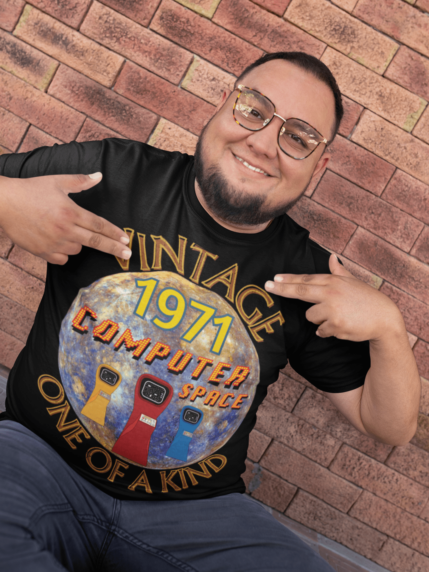 A man wearing black T-Shirt with the words vintage,1971,computer space,one of a kind,large earth, 3 computer space arcade machines