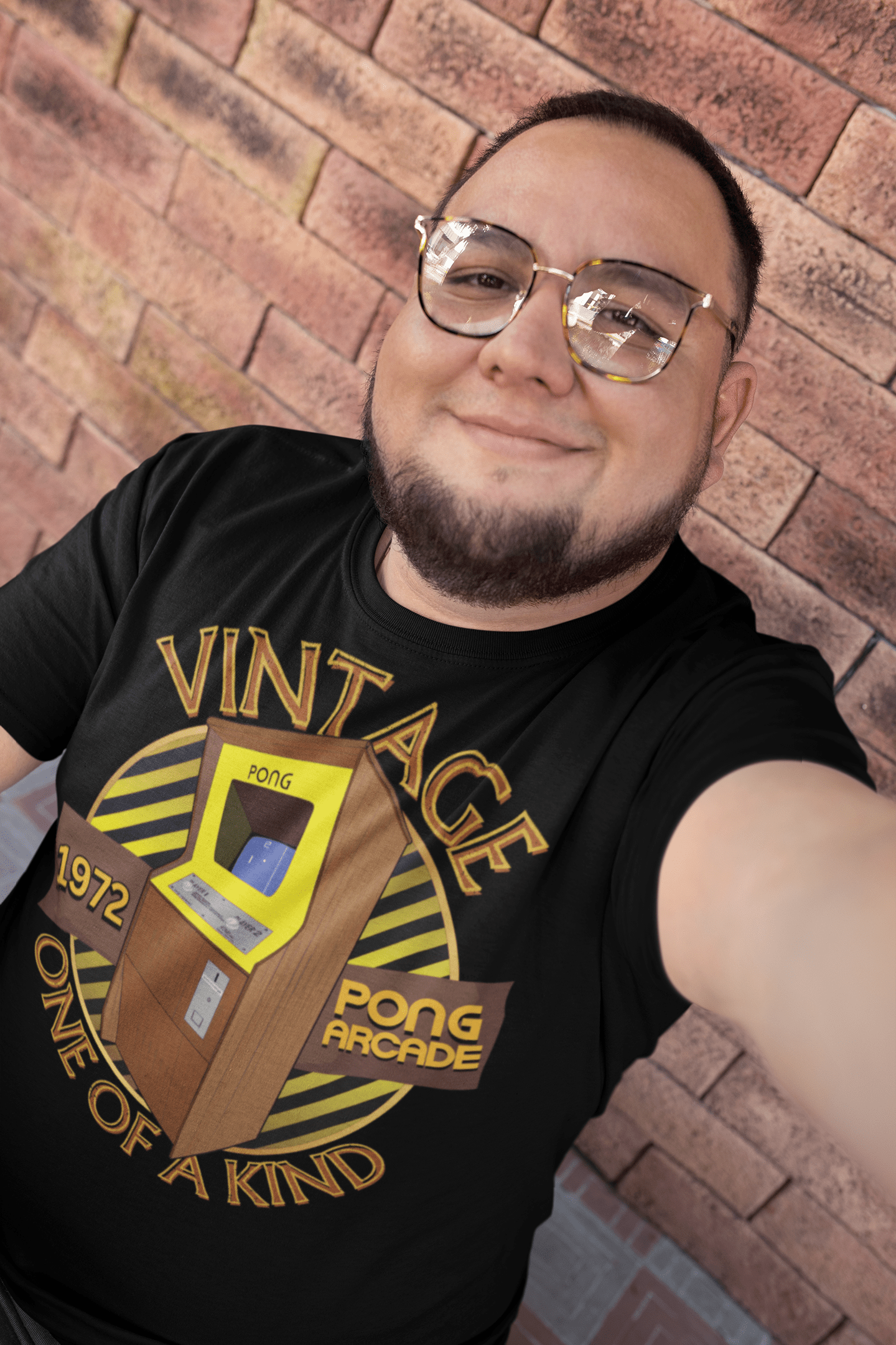 A man wearing a black T-Shirt with words vintage,1972,pong arcade,one of a kind, image of a pong arcade machine in front of a yellow striped circle