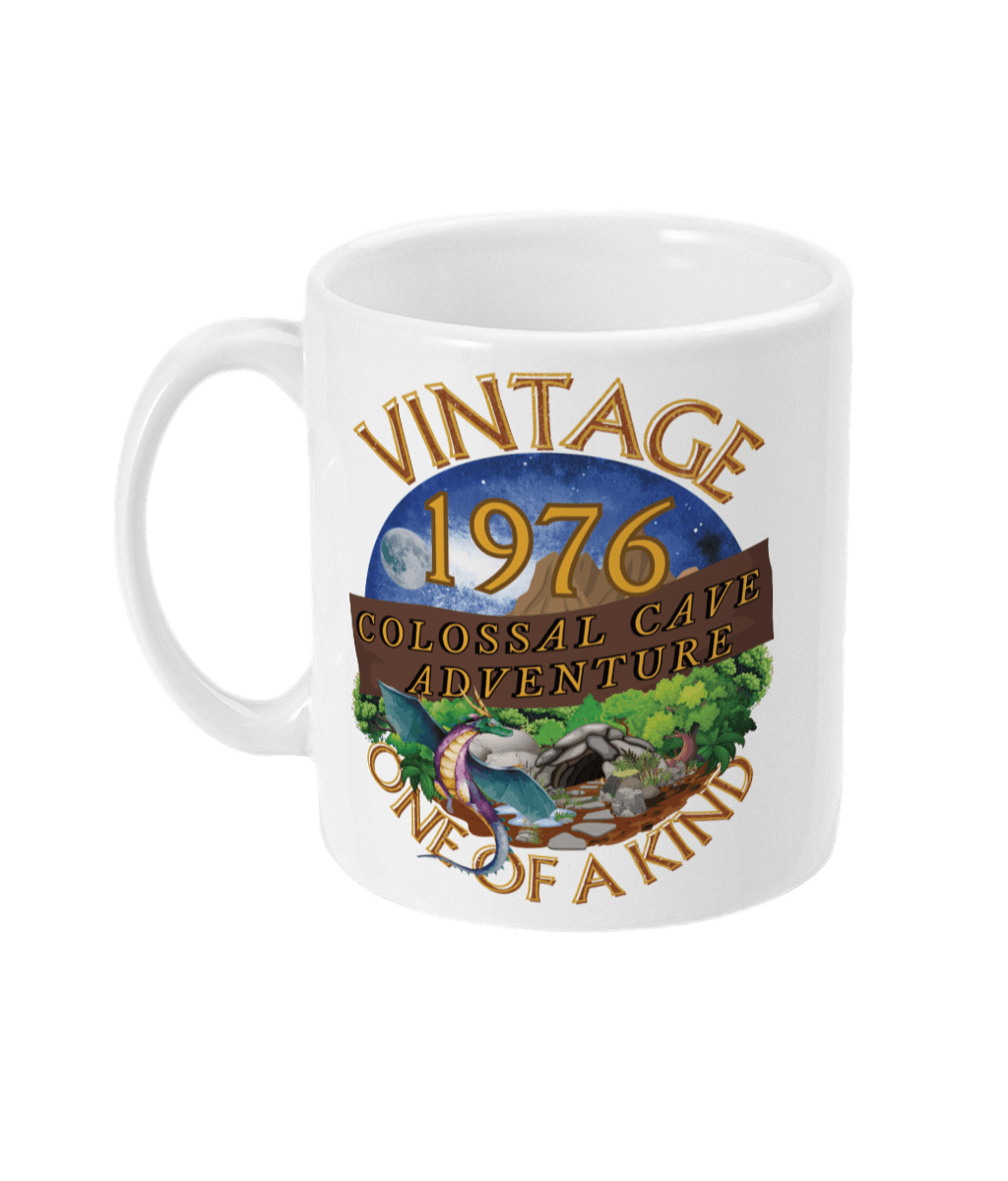 White mug with words,1976,colossal cave adventure,circular picture of a dragon,cave and woodland,night sky