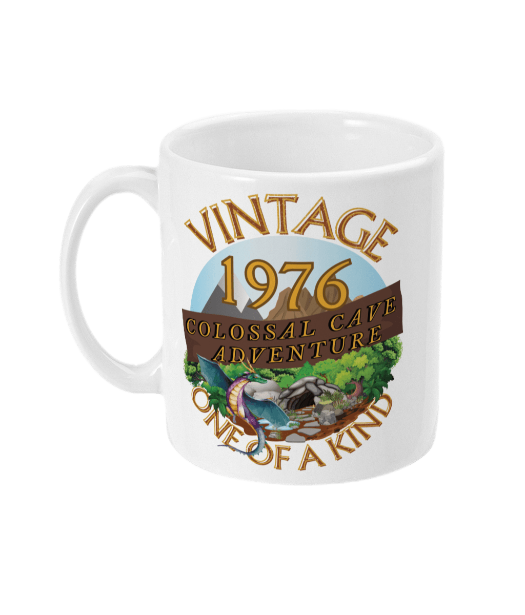 White mug with words vintage,1976,colossal cave adventure,one of a kind,circular picture of a dragon,cave and woodland,blue sky