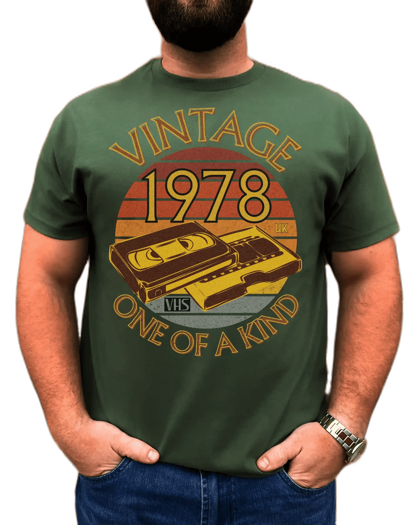 A man wearing green T-shirt browny, sunset circle vintage and one of a kind around it,numbers 1978 UK in  circle & an image of a VHS tape and cover box